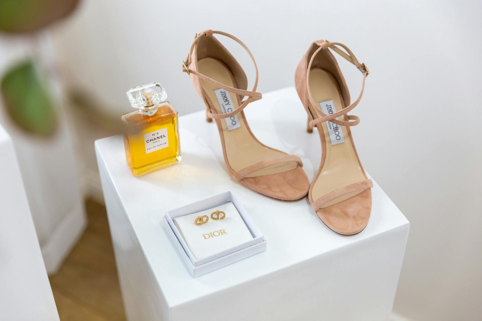 Chic display of luxury sandals, perfume, and jewelry on elegant stands.