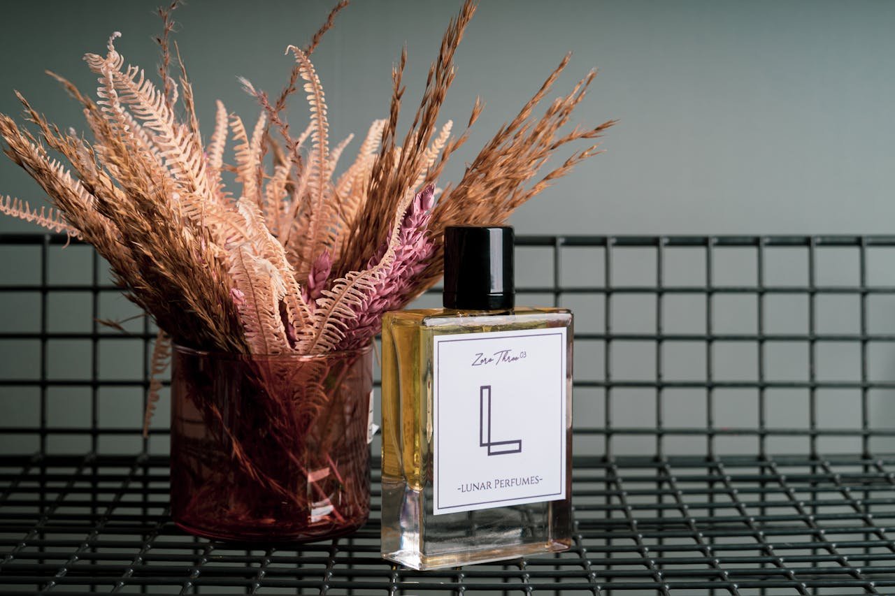 our-journey-02 Elegant perfume bottle and dried flowers on a wire grid surface, perfect for luxury and aroma themes.
